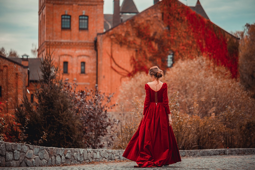 Czerwona suknia ślubna. Panna młoda w czerwonej sukni ślubnej na tle jesiennego zamku.