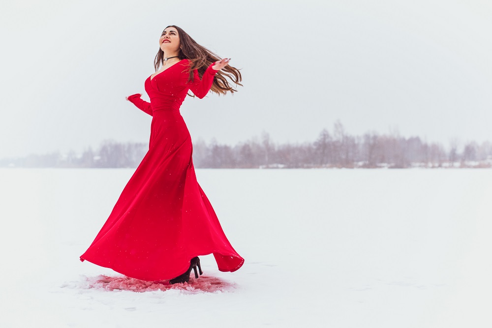 Czerwona suknia ślubna. Panna młoda w czerwonej sukni tańczy na śniegu.