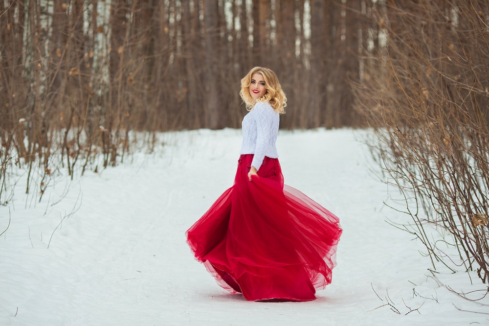 Czerwona suknia ślubna. Panna młoda w czerwonej sukni i białym bolerku tańczy w lesie. 