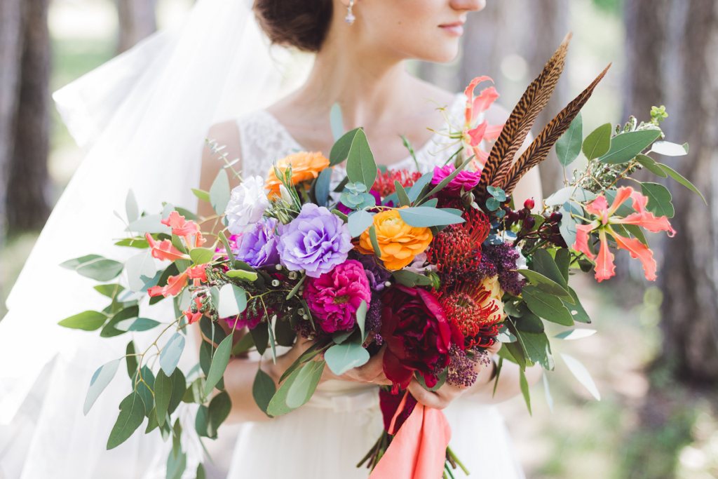 Bukiet ślubny z piórami wykonany z kolorowych kwiatów