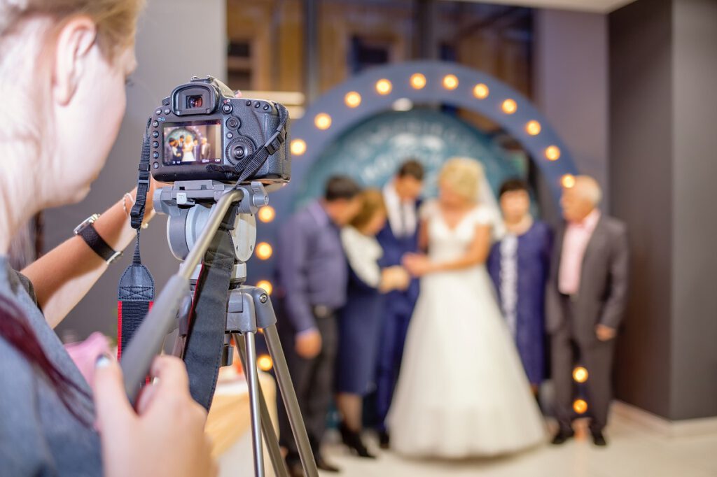 jak wybrać kamerzystę na wesele - filmowiec nagrywający parę młodą na ściance