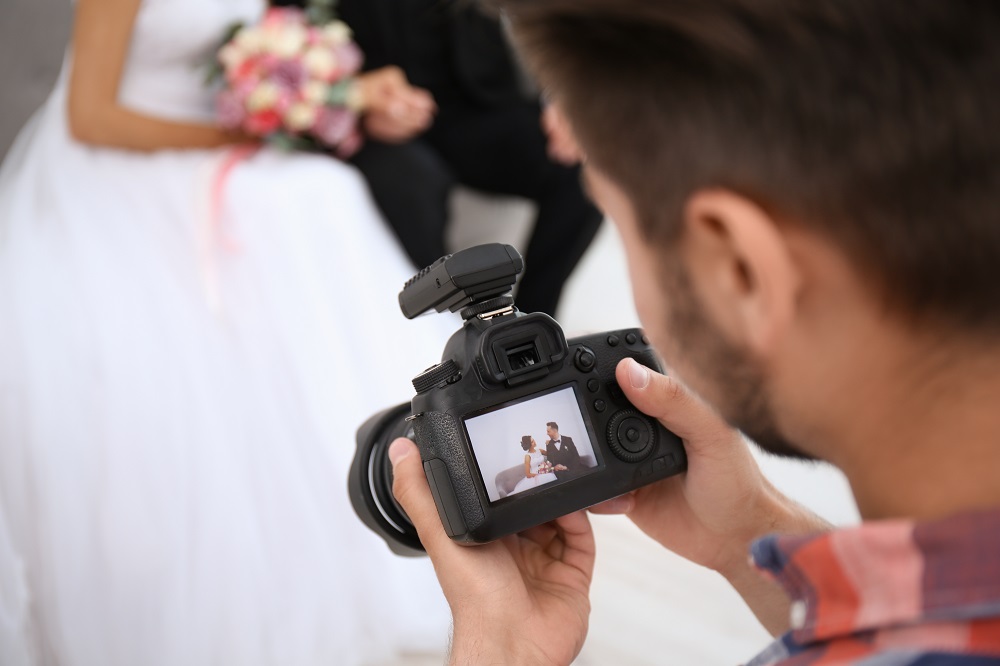 Jak wybrać fotografa ślubnego - fotograf ogląda zdjęcia z sesji ślubnej