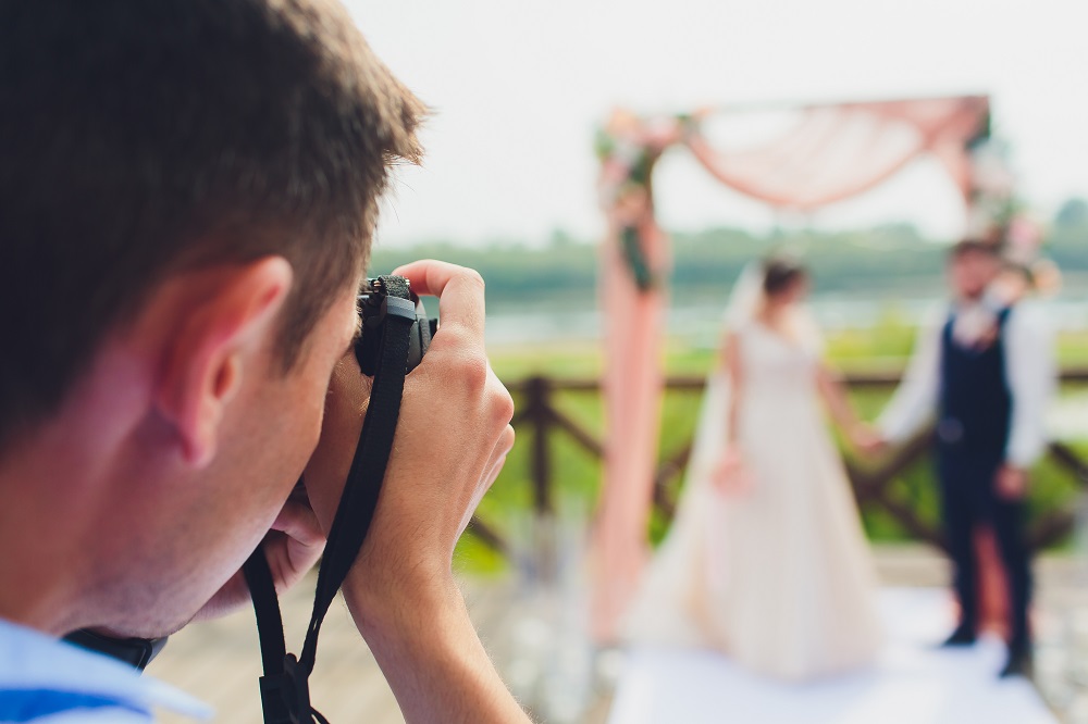 Jak wybrać fotografa ślubnego - para młoda pozuje na ściance ślubnej w plenerze