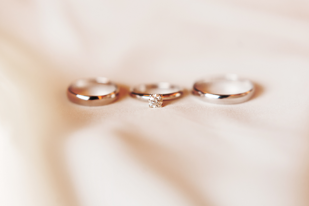 Jak nosić pierścionek zaręczynowy i obrączkę - pierścionek zaręczynowy i obrączka leżące na materiale 