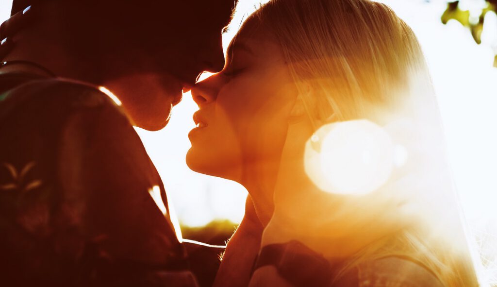 rocznice ślubu w innych krajach - Pocałunek pary na tle zachodzącego słońca