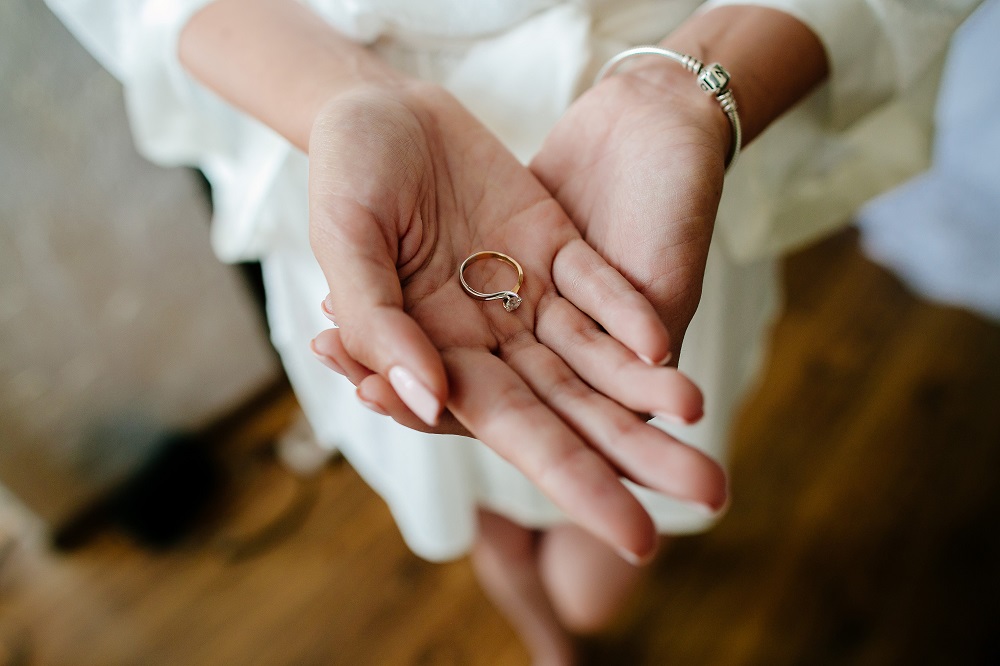 Zaręczyny - kobieta trzyma w dłoniach pierścionek zaręczynowy