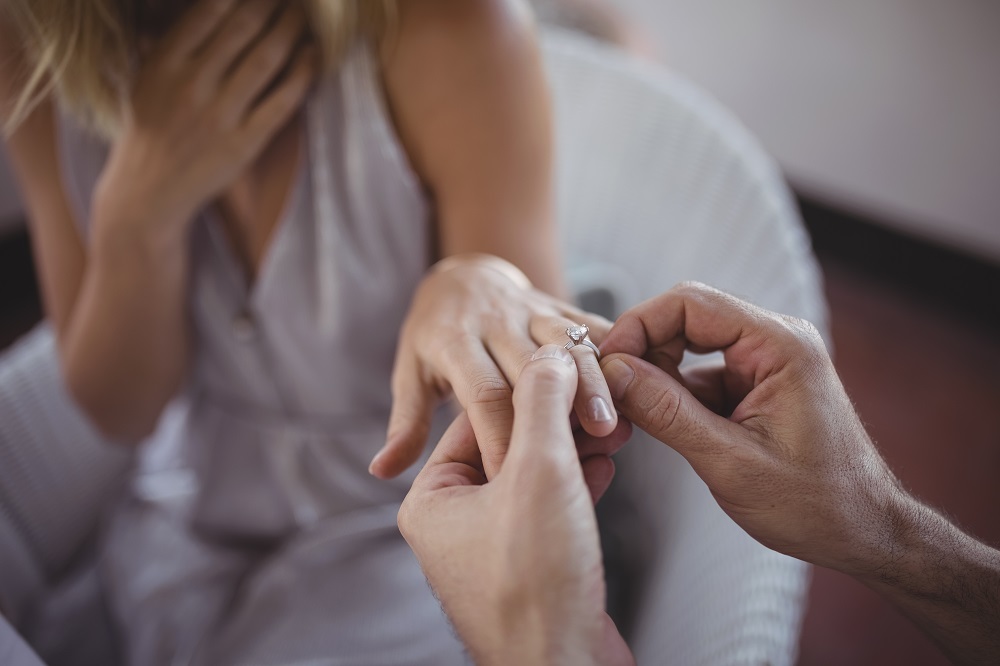 Zaręczyny - mężczyzna nakłada kobiecie pierścionek zaręczynowy