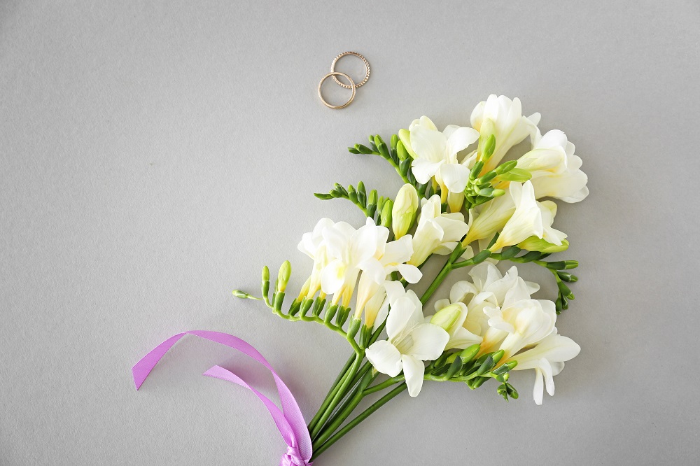 Kwiaty do bukietu ślubnego. Gałązka frezji związana fioletową wstążką.