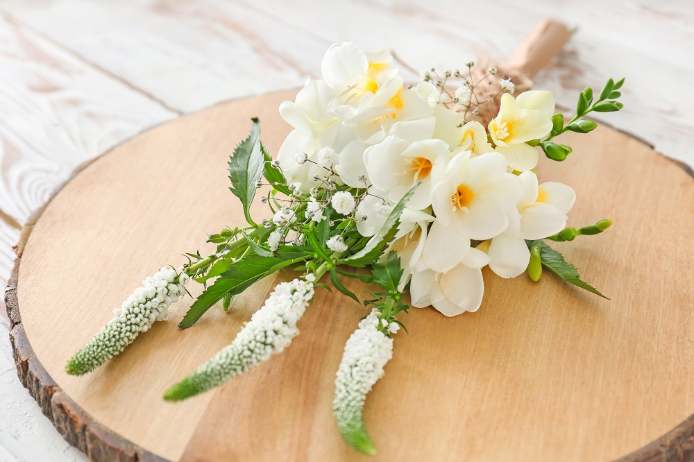 Kwiaty do bukietu ślubnego. Bukiet białych frezji na podkładce z drewna.