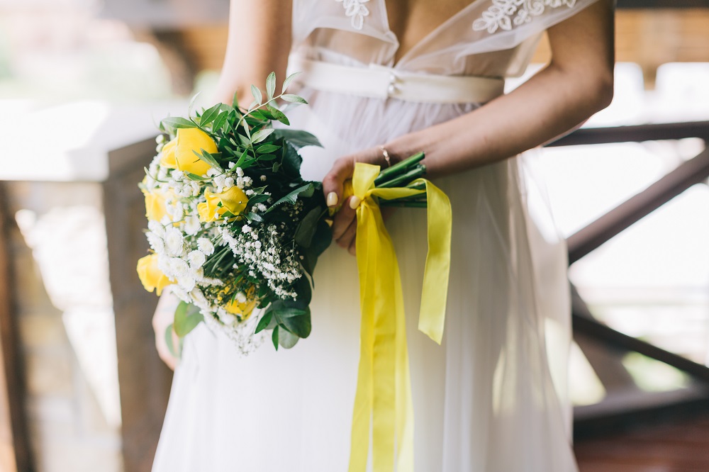 Kwiaty do bukietu ślubnego. Bukiet z żółtych róż i gipsówki związany wstążką.