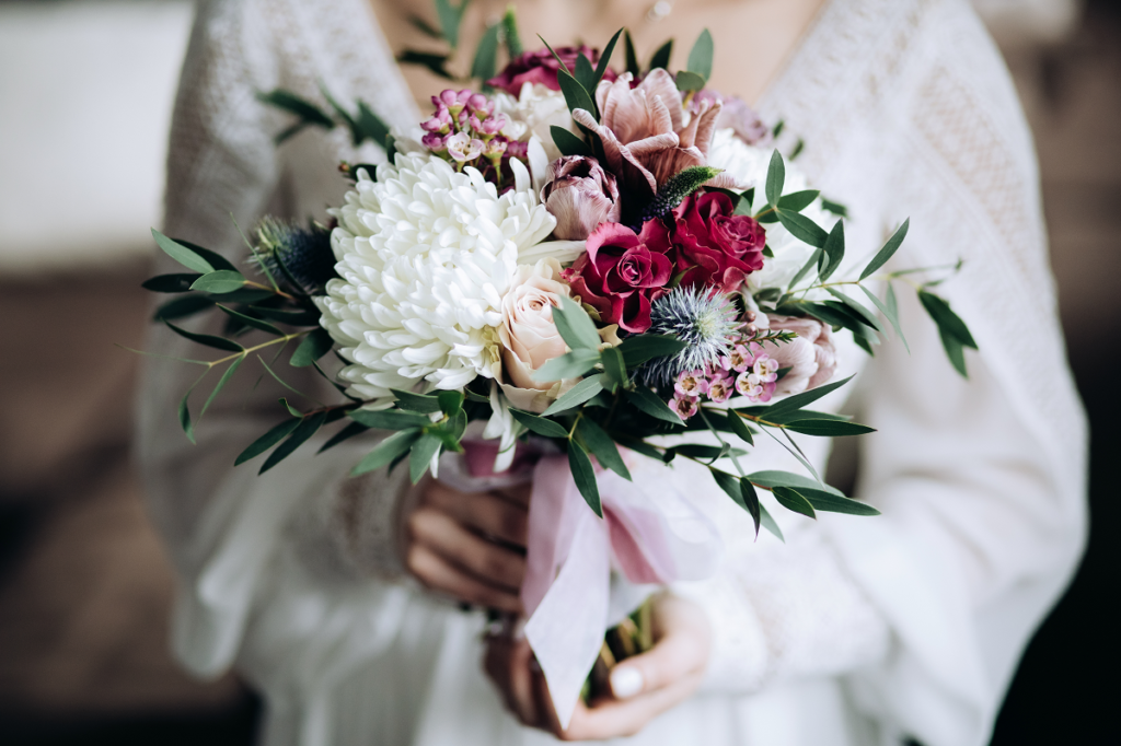 Bukiet ślubny z bordowych i białych kwiatów w rękach panny młodej