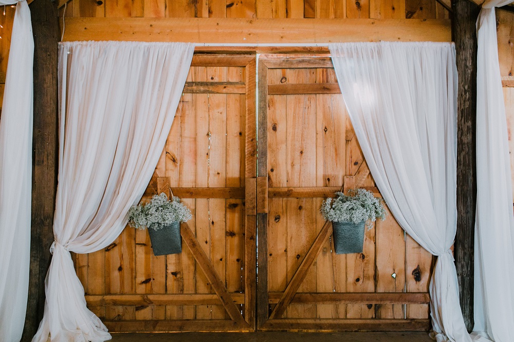 Wesele w stodole - drzwi stodoły przyozdobione białymi zasłonami