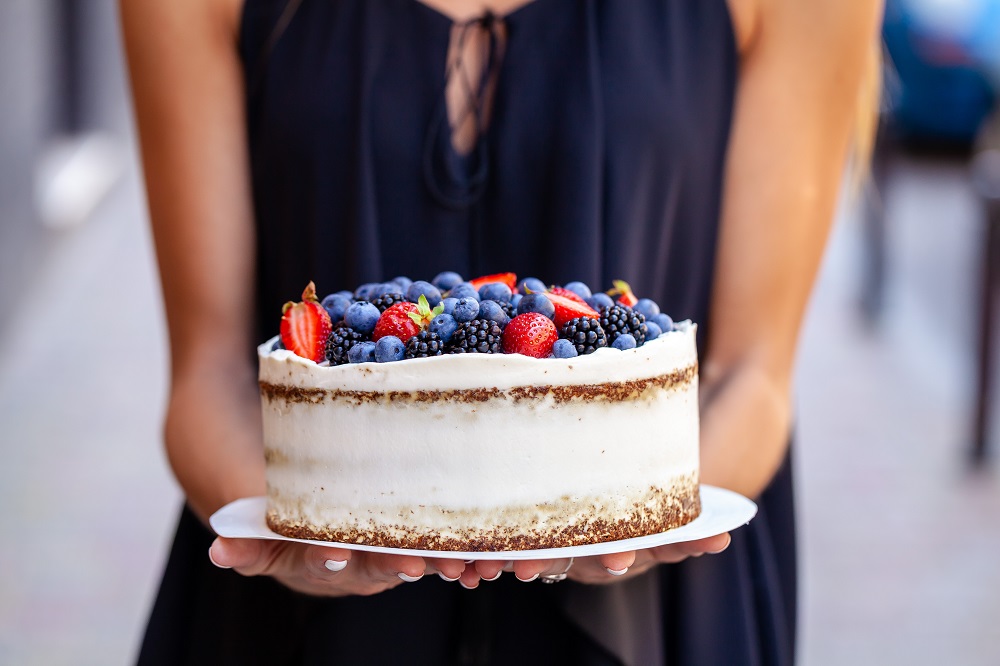 Ciasta na wesele - kobieta trzymająca ciasto z owocami