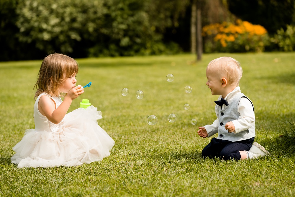 Kącik dla dzieci na weselu. Chłopiec i dziewczyna puszczający banki mydalne.