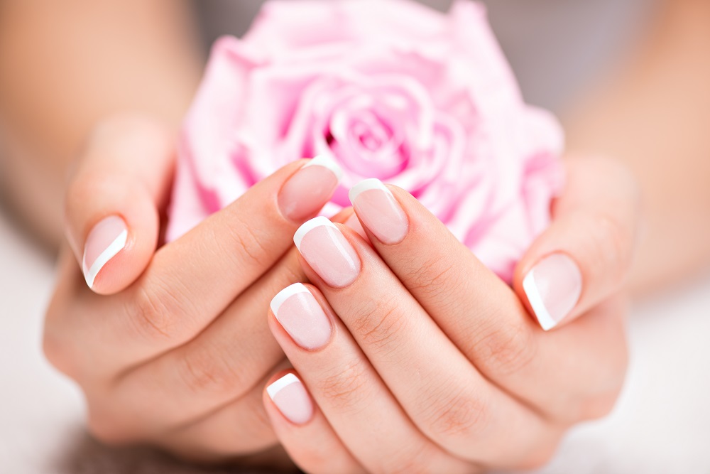 Kształty paznokci - dłonie kobiety trzymające różę