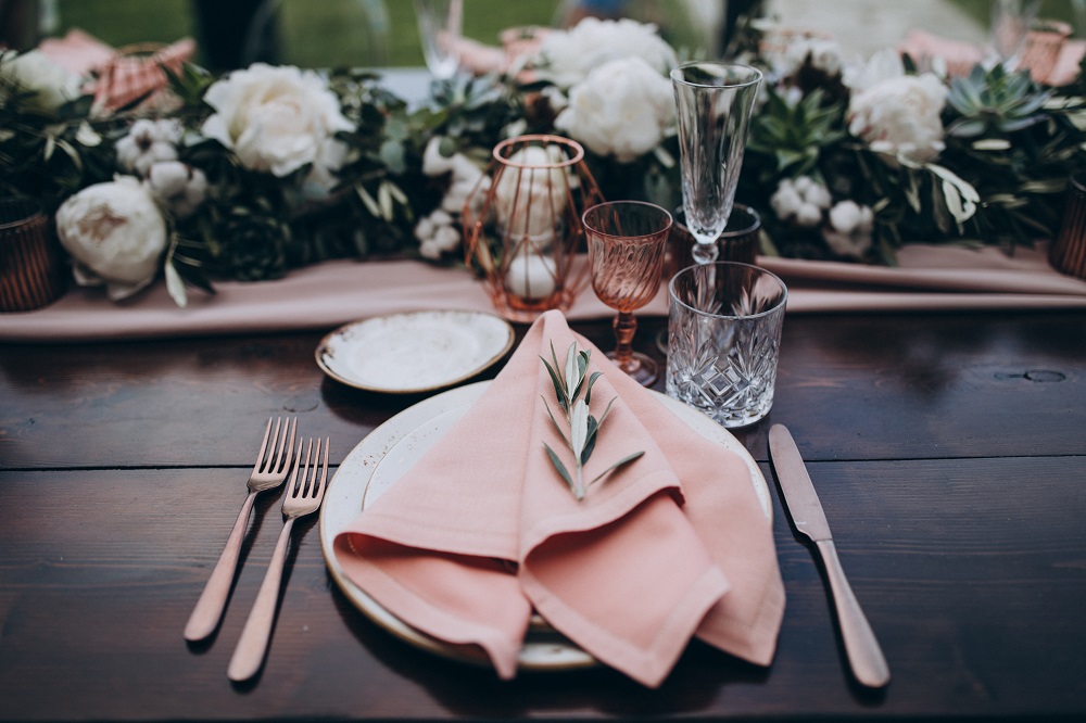 style weselne - piękna, różowa serweta na talerzu na stole weselnym