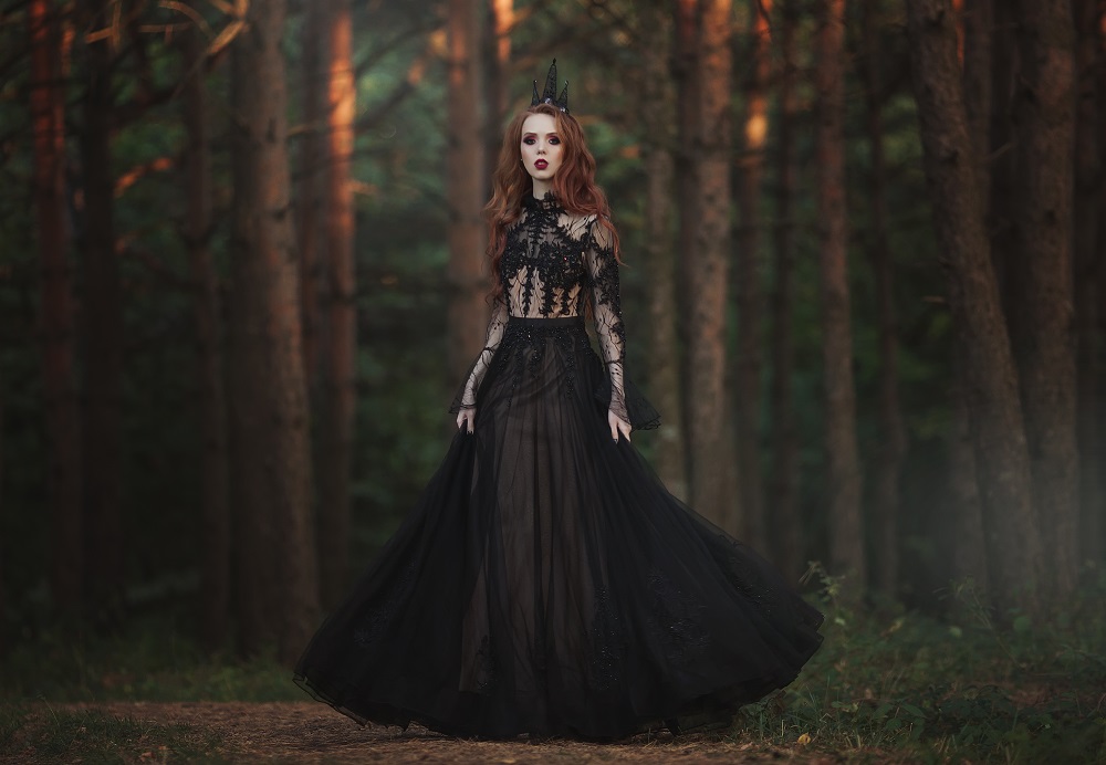 Kolorowe suknie ślubne. Kobieta w czarnej, koronkowej sukni w lesie.