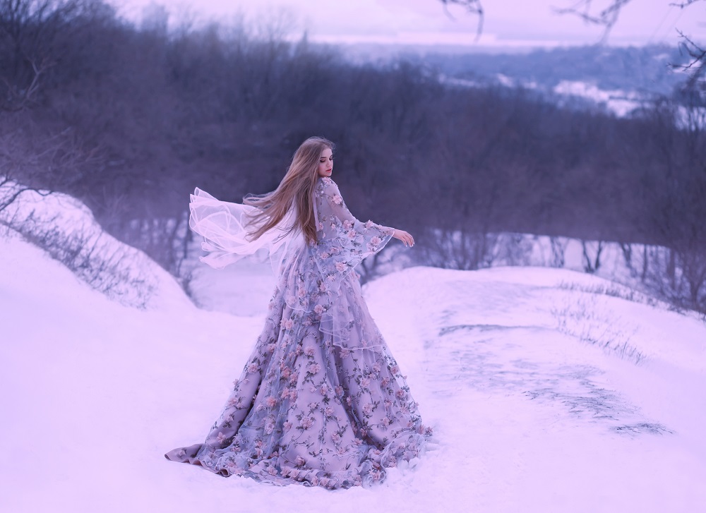 Kolorowe suknie ślubne. Śliczna dziewczyna w fioletowej, długiej sukni podczas zimowej sesji w lesie.
