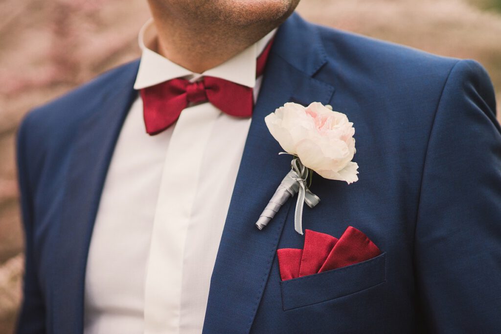 garnitur ślubny - mężczyzna w garniturze z czerwoną muszą i poszetką