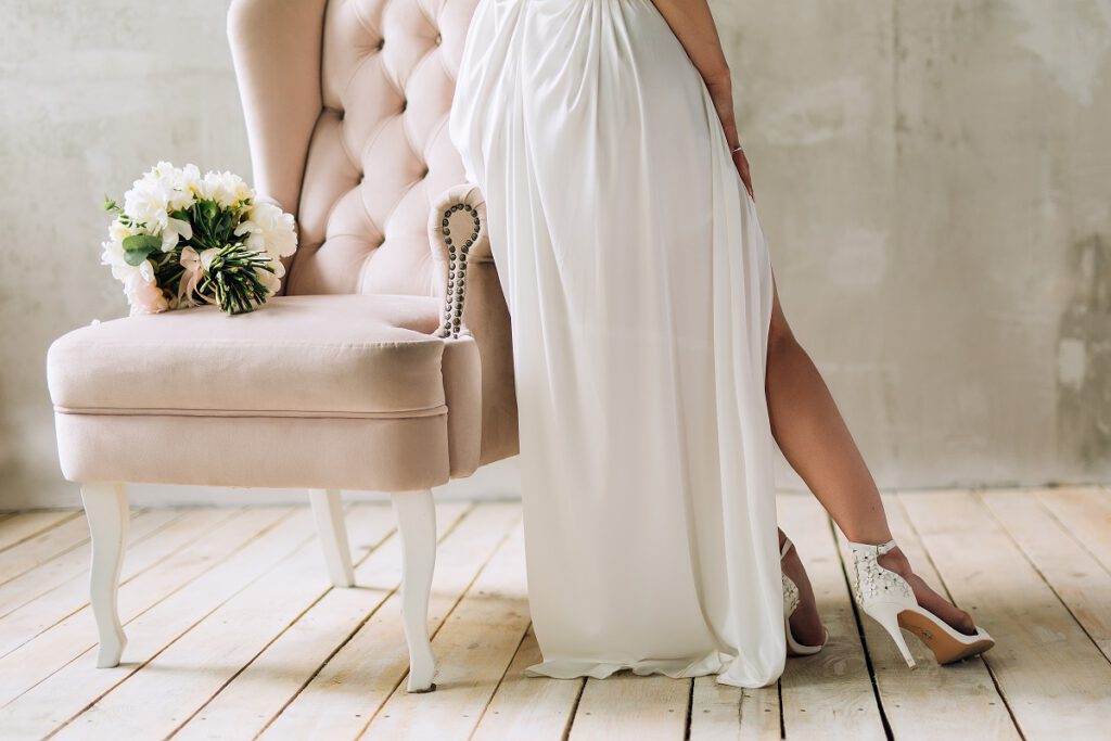 suknia ślubna z rozcięciem - panna młoda siedząca na fotelu