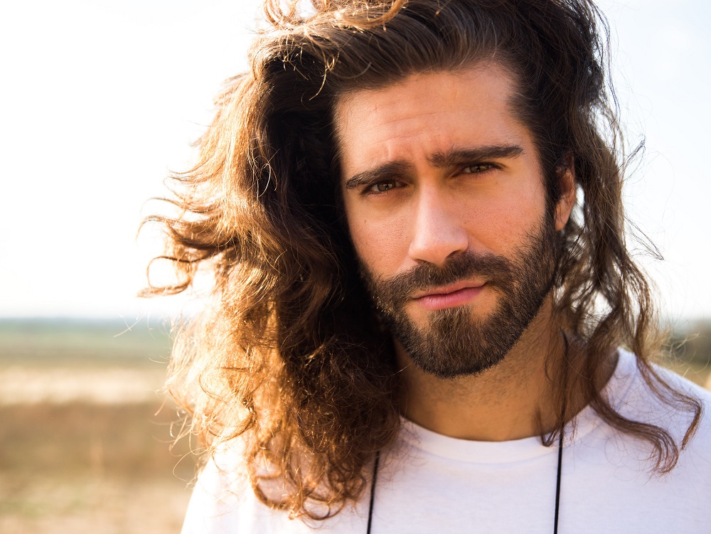 Fryzury męskie na długie włosy  - mężczyzna z zarostem i długimi kręconymi włosami