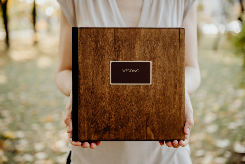 Album ślubny - damskie dłonie trzymają drewniany album