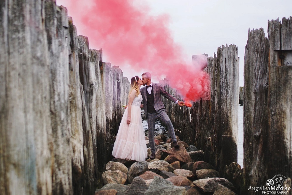 Kolorowy dym na wesele - para młoda podczas sesji nad morzem z różowym dymem
