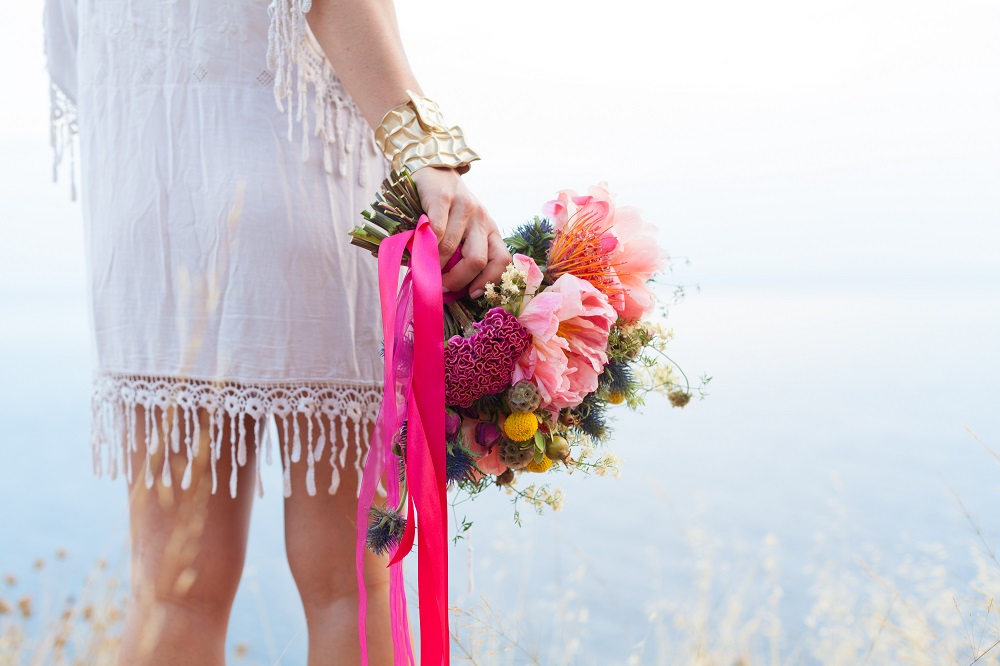 Bukiet ślubny boho. Bukiecik ślubny w stylu boho z kolorowych kwiatów związany różowymi wstążkami.