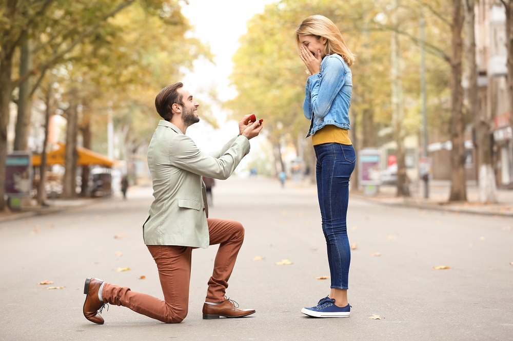 sennik zaręczyny - mężczyzna klęczy przed kobietą i oświadcza jej się