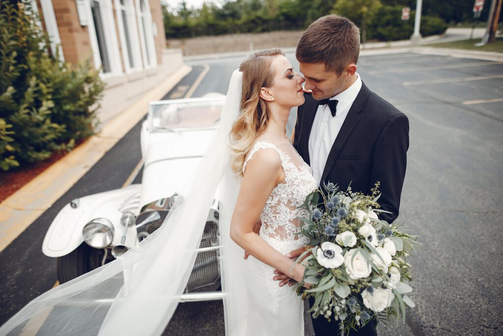 klasyczna suknia ślubna - para młoda na tle zabytkowego samochodu