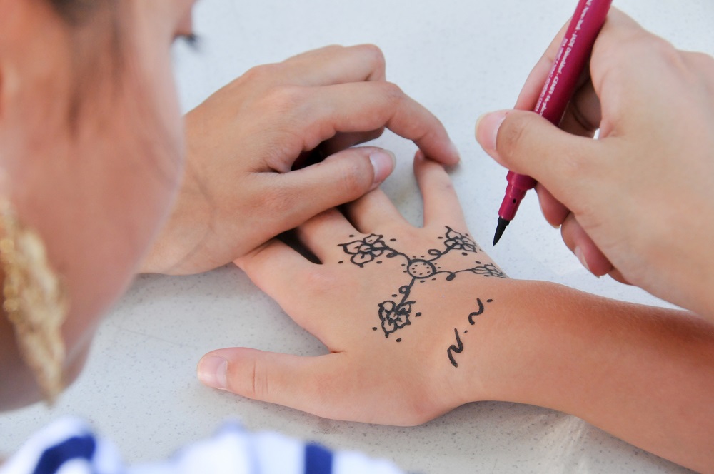 Tatuaż obrączka - kobieta maluje wzory na ręce.