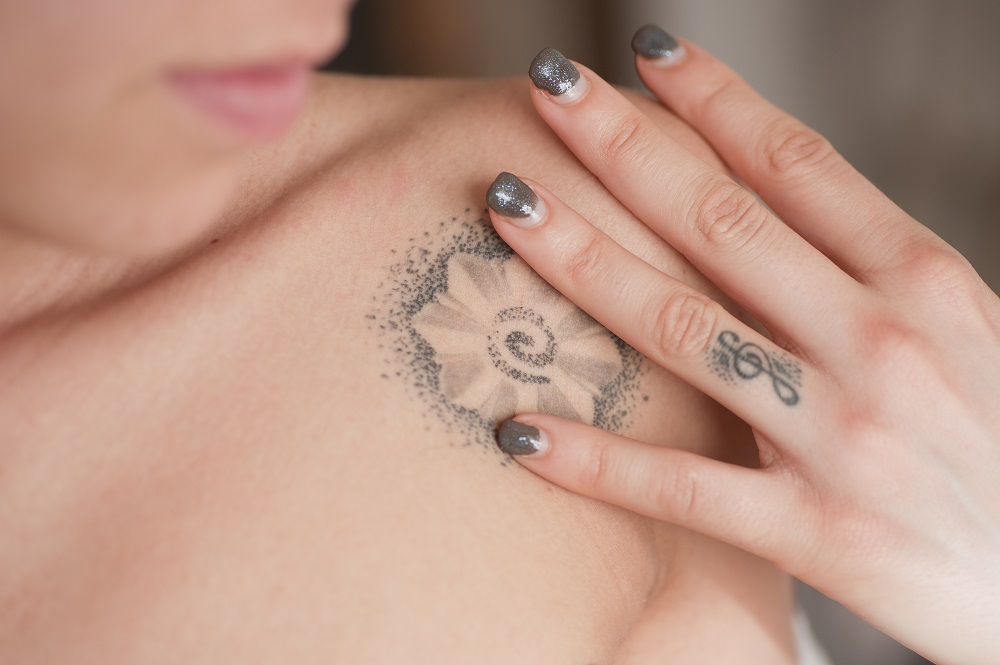 Tatuaż obrączka - zdjęcia kobiety z tatuażem na obojczyki u palcu.