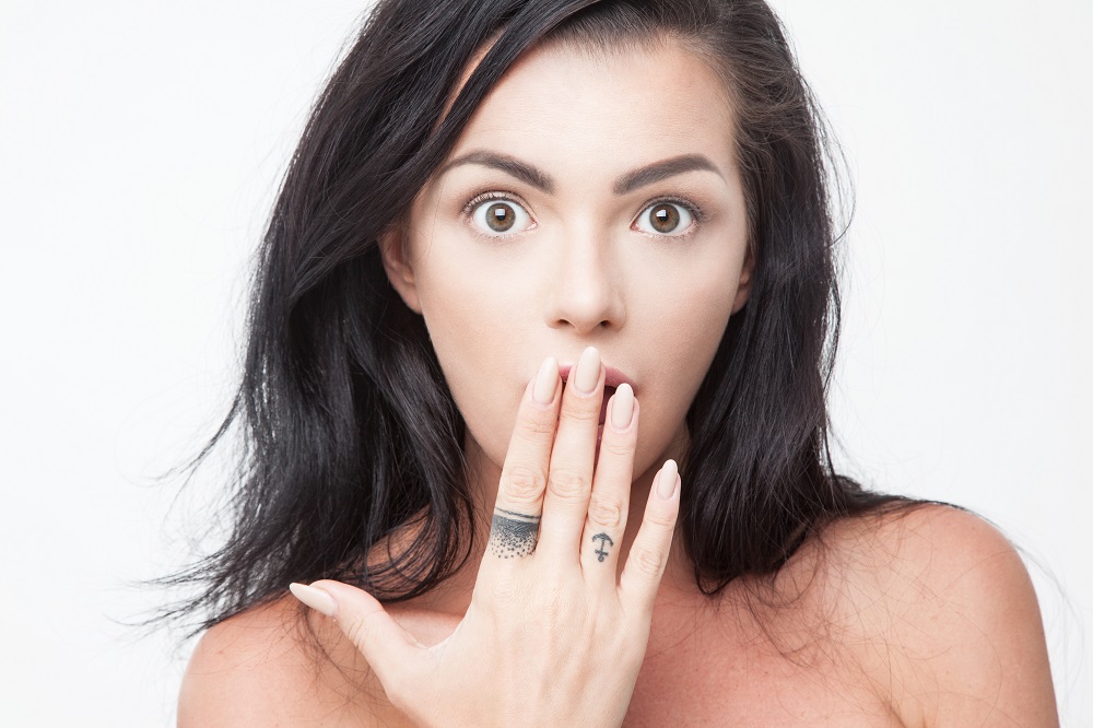 Tatuaż obrączka - kobieta zakrywa twarz dłonią z tatuażami na palcach