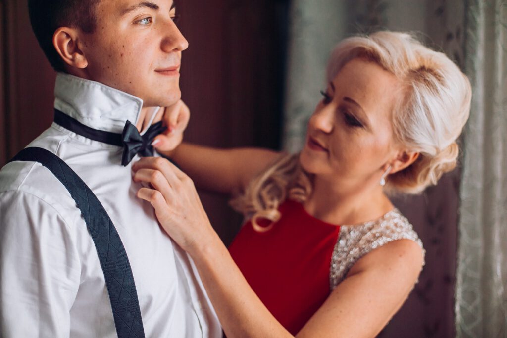 sukienka na wesele dla 50 latki - matka pana młodego poprawia mu muszkę