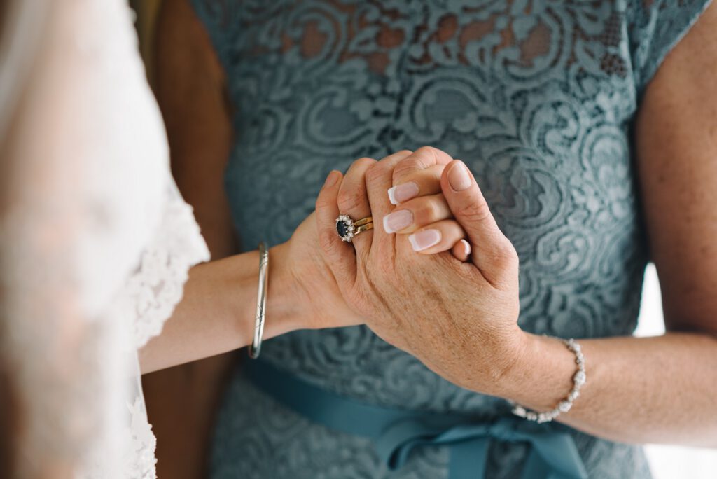 Sukienka na wesele dla 50 latki - starsza kobieta w niebieskiej sukience trzyma za rękę pannę młodą