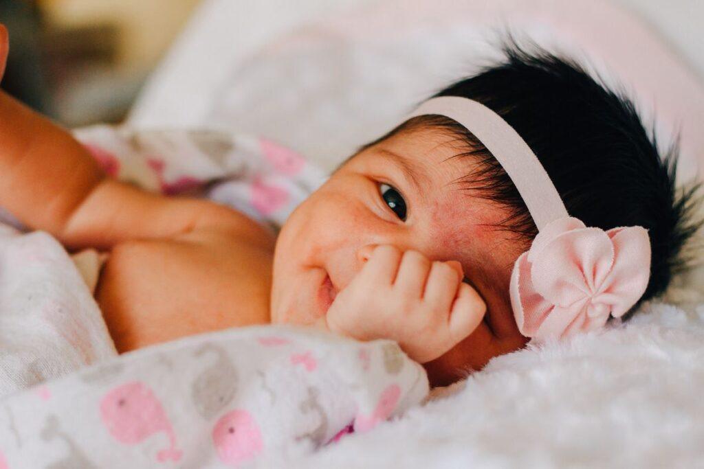 Imiona dla dziewczynek - noworodek w różowej opasce z kwiatkiem