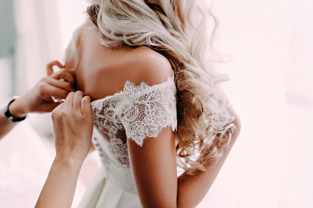 suknia ślubna koronka - panna młoda wkładająca koronkową suknię