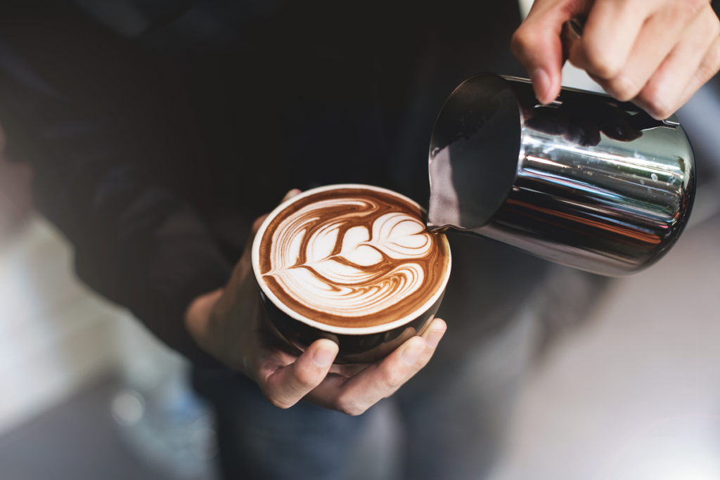 Barista na weselu tworzący wzór na kawie techniką latte art