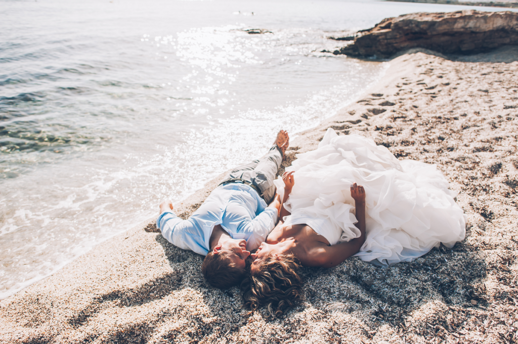 Ślub na plaży - nowożeńcy leżący na piasku