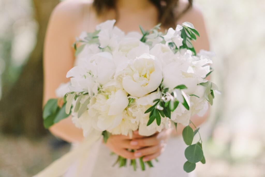 panna młoda trzymająca w ręku piękny bukiet z białych kwiatów 