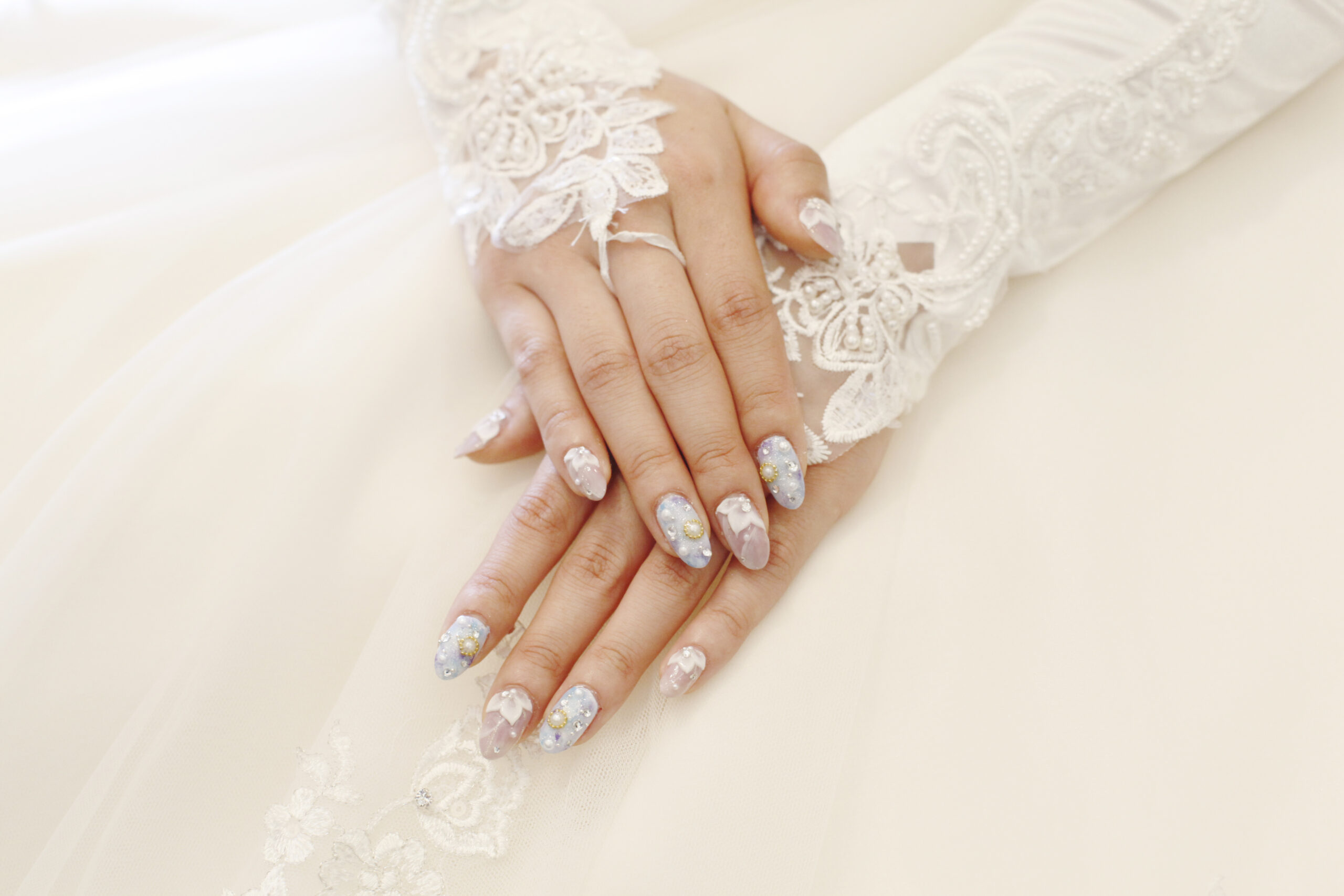 delikatne perłowe paznokcie na ślub z ozdobami na dłoniach panny młodej