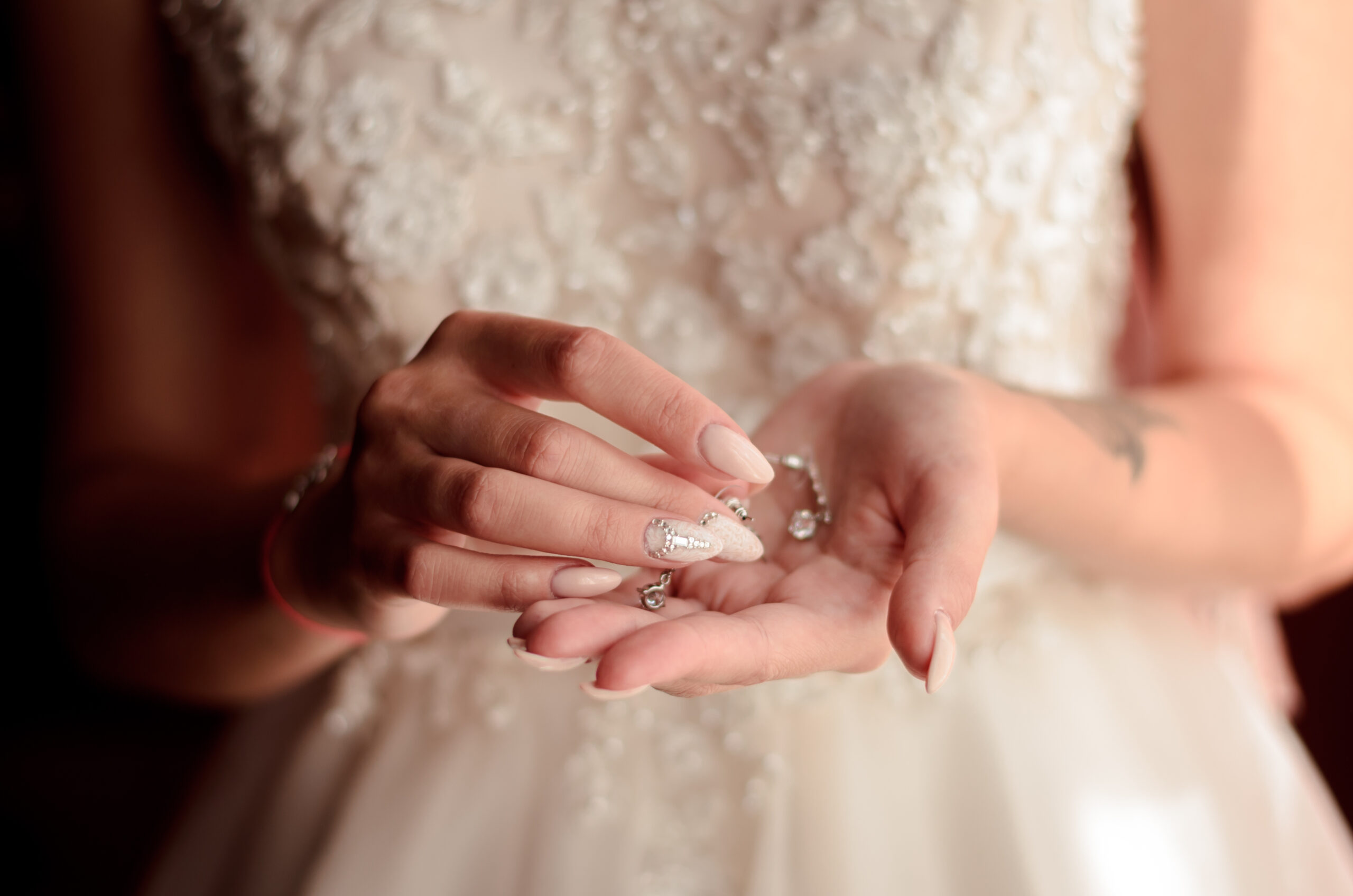 paznokcie ślubne nude z ozdobnymi cyrkoniami na dłoniach panny młodej