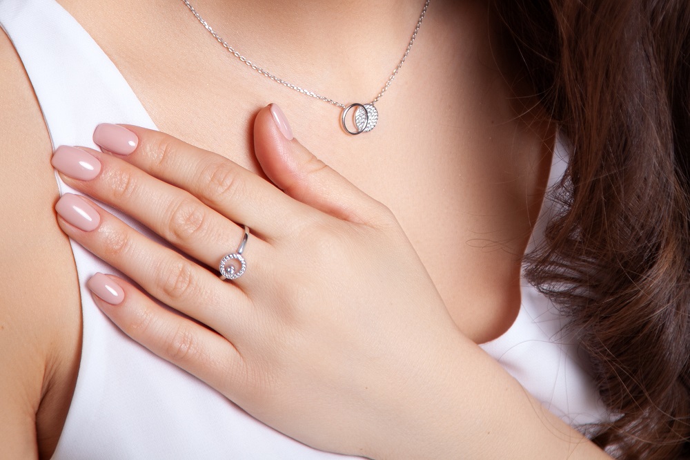 na którym palcu nosi się pierścionek zaręczynowy - kobieta z powieszonym pierścionkiem na szyi