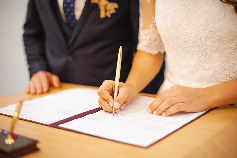 Ślub cywilny. Para młoda podpisująca akt małżeństwa.