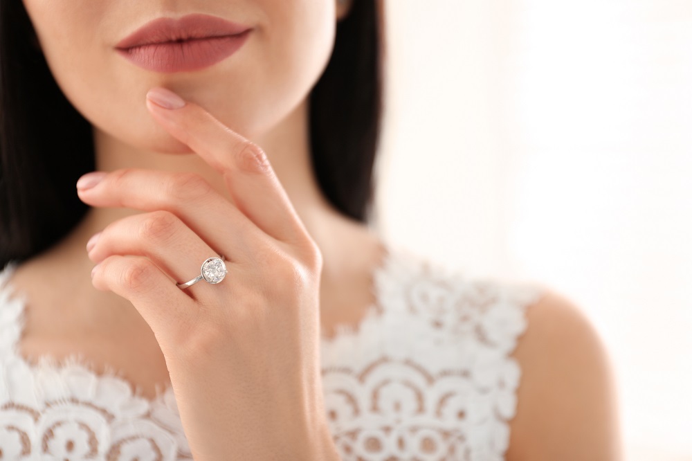 na którym palcu nosi się pierścionek zaręczynowy - kobieta dotyka twarzy dłonią z pierścionkiem zaręczynowym