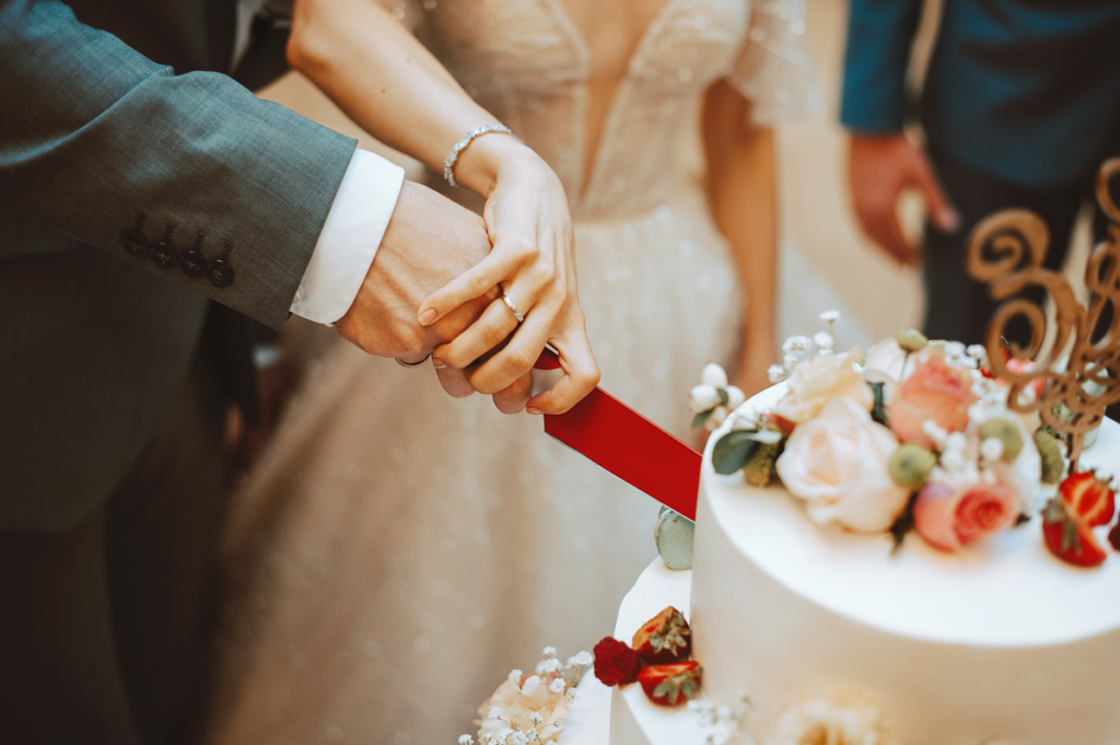 Para młoda krojąca wspólnie tort weselny