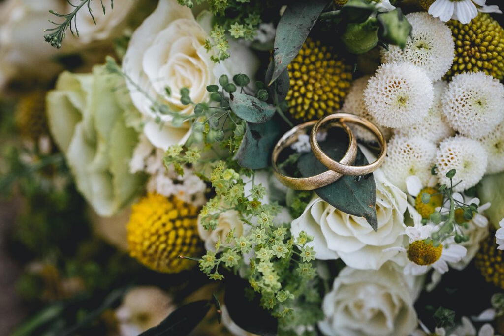 Ślub jednostronny - złote obrączki ślubne leżące na bukiecie
