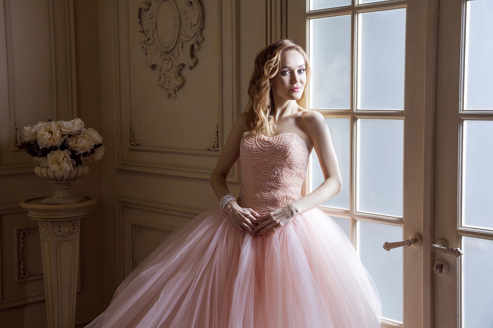 Różowa suknia ślubna. Panna młoda w różowej sukni pozuje w pałacu.