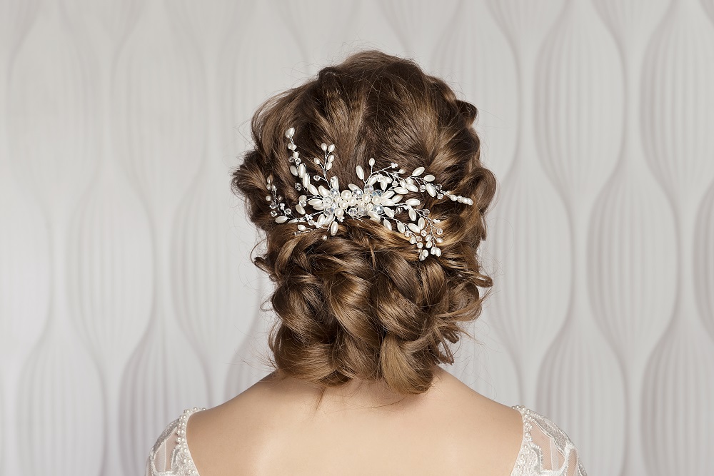 Niskie upięcie na ciemnych włosach z ozdobą jako przykład fryzury na wesele.