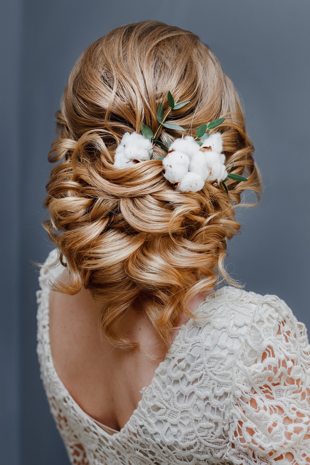 Zmysłowe upięcie włosów z ozdobą z bawełny jako przykład fryzury na wesele.